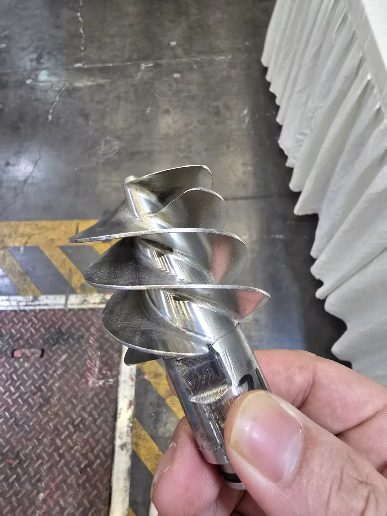 Close view of a precision-machined spiral metal component being verified.