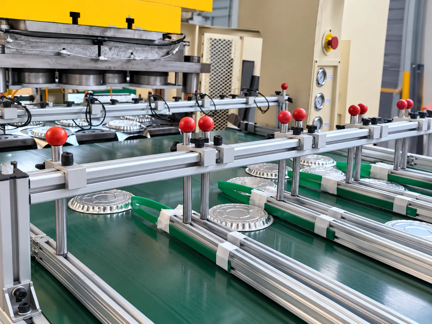 Aluminum foil food containers moving through production equipment in a China factory.